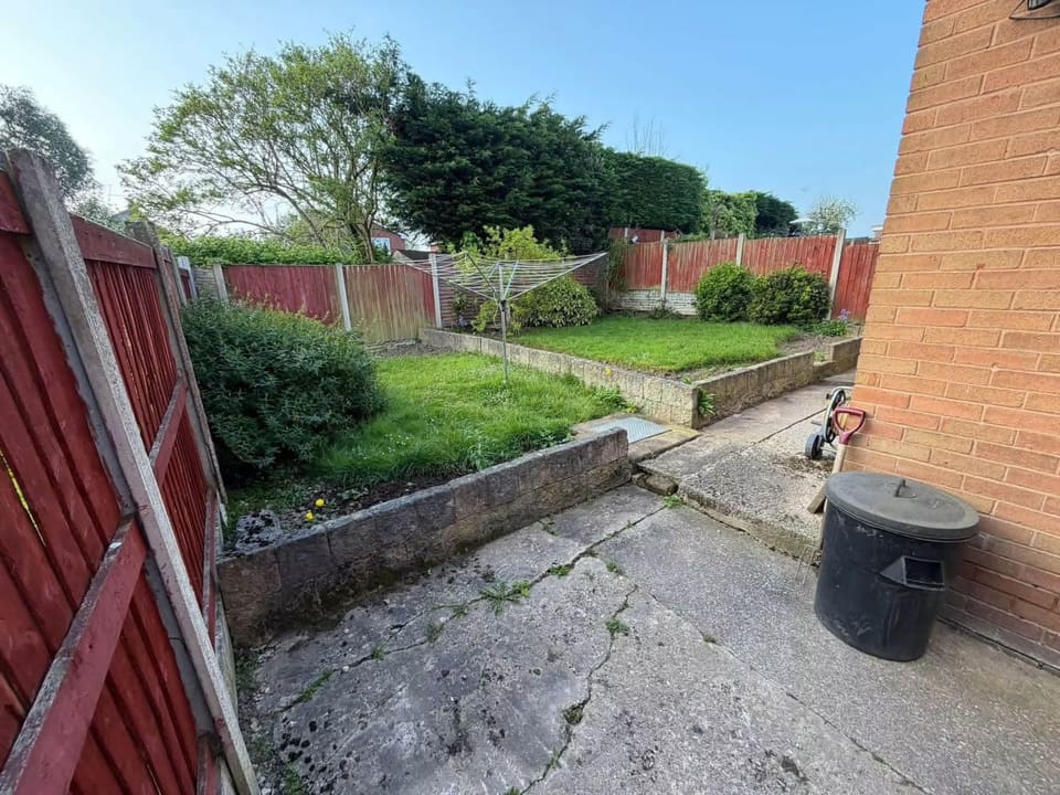 The same garden from the same spot before: cracked concrete and a tired lawn.