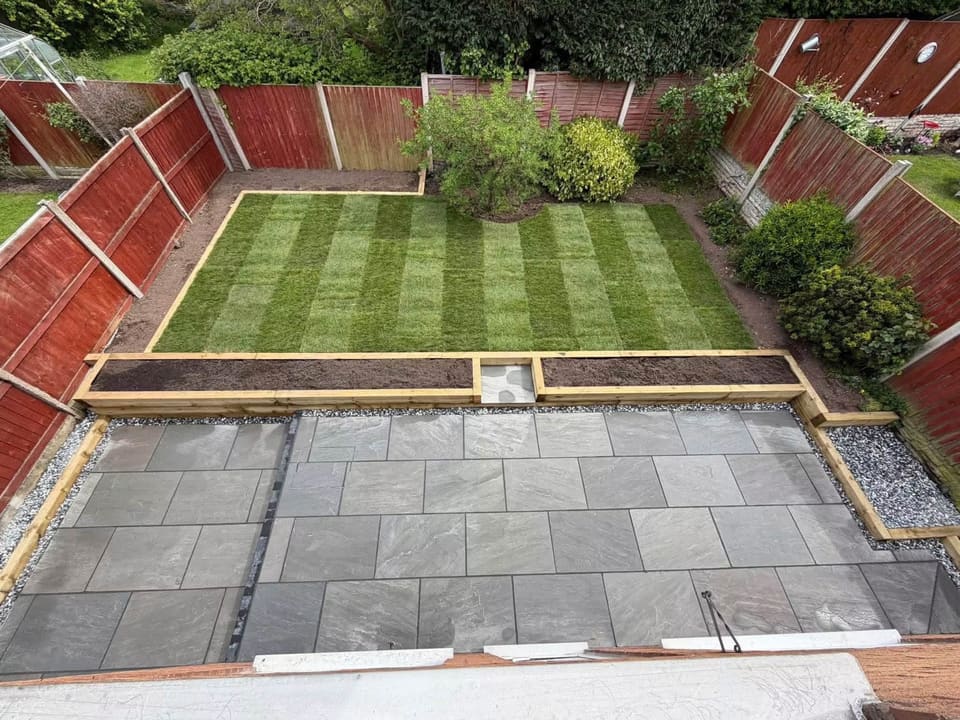 A finished back garden from an upstairs window: riven porcelain, a gravel margin, a sleeper edge and striped turf.