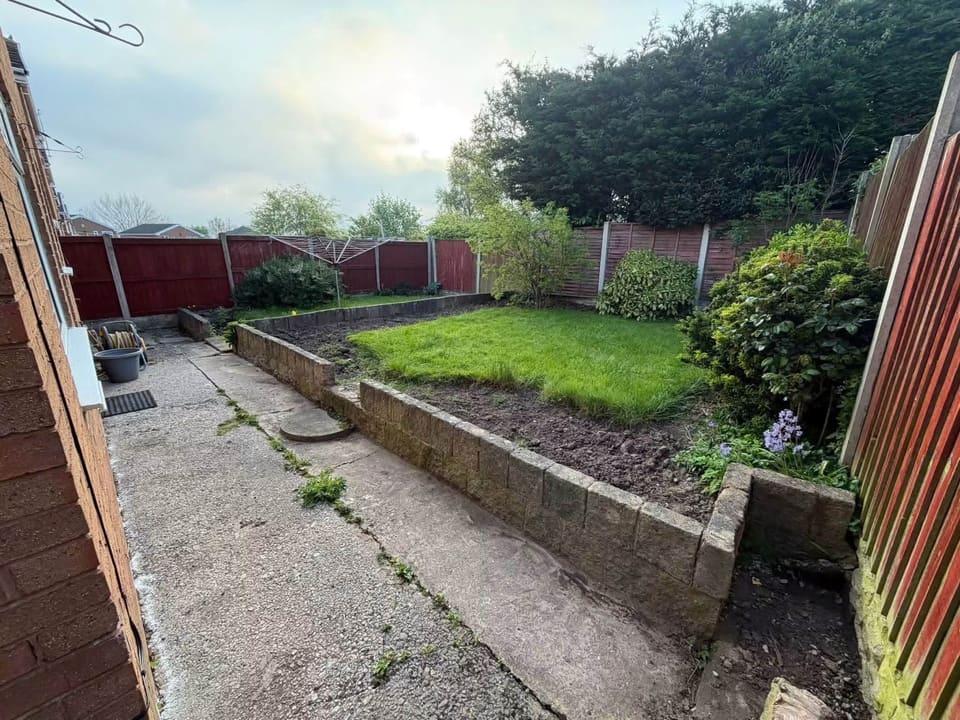 The same garden before the work: cracked concrete, a concrete block wall and tired grass.