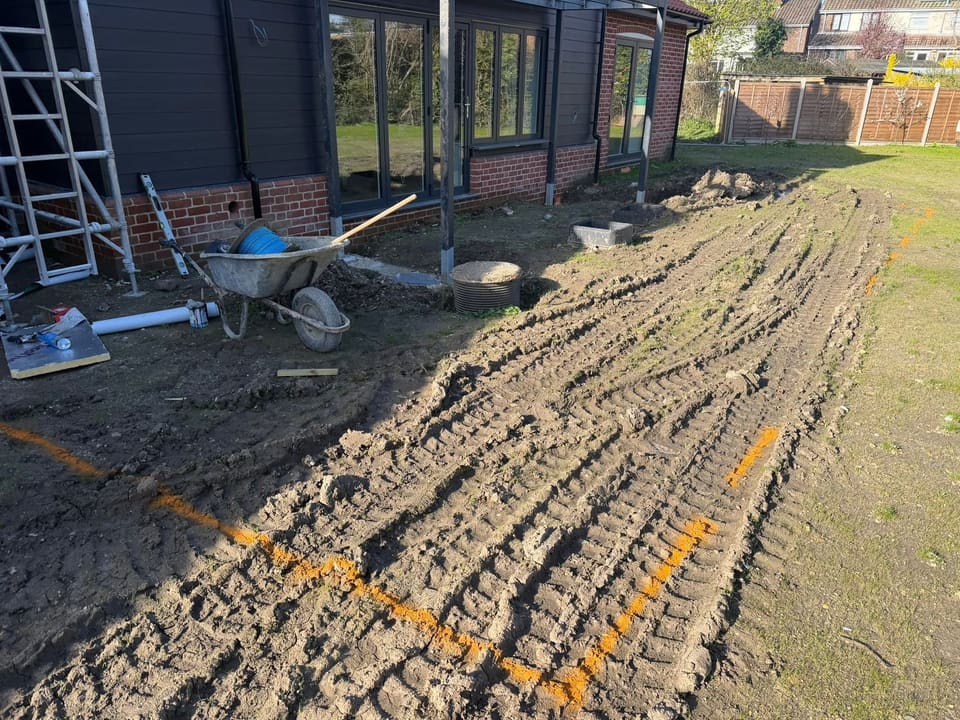 The same ground set out in orange marker spray, with a drainage chamber and a gully in the dug earth.