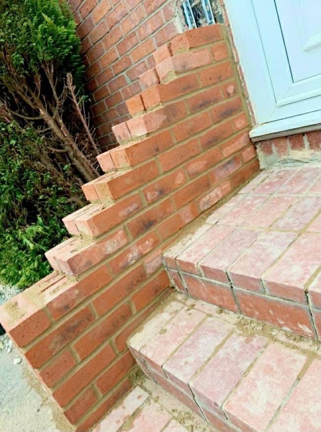 A close view of new brick steps and the corner of a raked cheek wall.