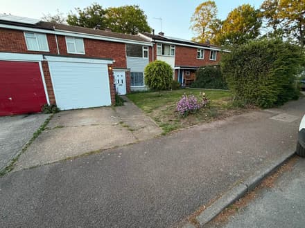 The same frontage before the work, with worn tarmac and a patchy grass verge.