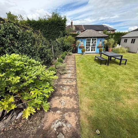 The same garden from the same spot before the work, with a narrow crumbling stone path and a bare border.