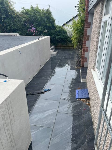 The same terrace from the other end, dark porcelain between the house wall and the new rendered retaining wall.