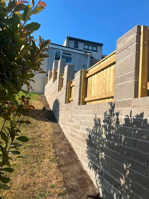 A new blockwork retaining wall stepping up a slope, with close board fence panels set between piers along the top.