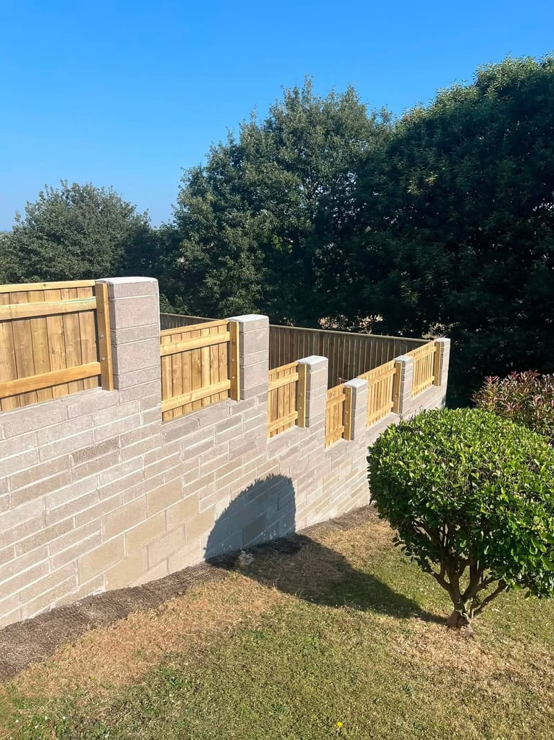 The same blockwork retaining wall from the far end, running the length of the boundary with close board fence panels along the top.