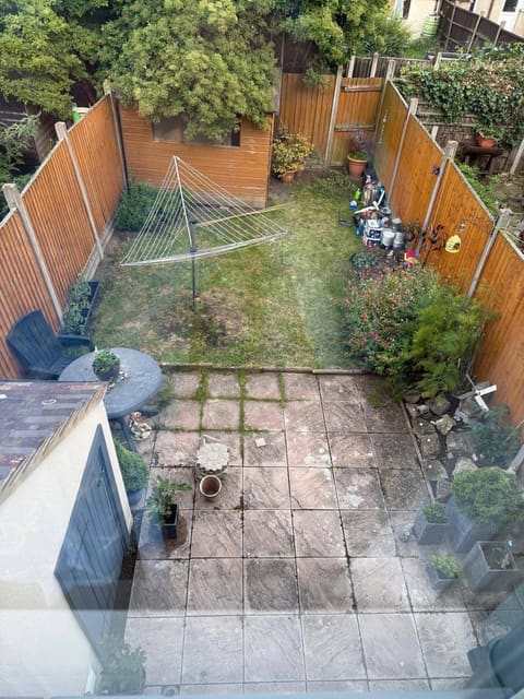 The same garden before the work, from the same upstairs window: cracked concrete slabs, a worn lawn and a rotary line.