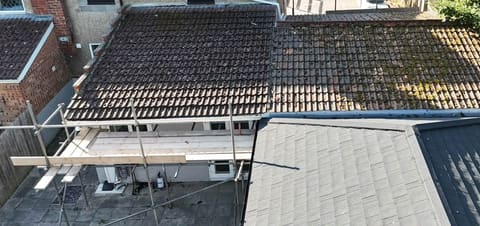 The same roof before the work, under old brown pantiles with moss and lichen across the courses.