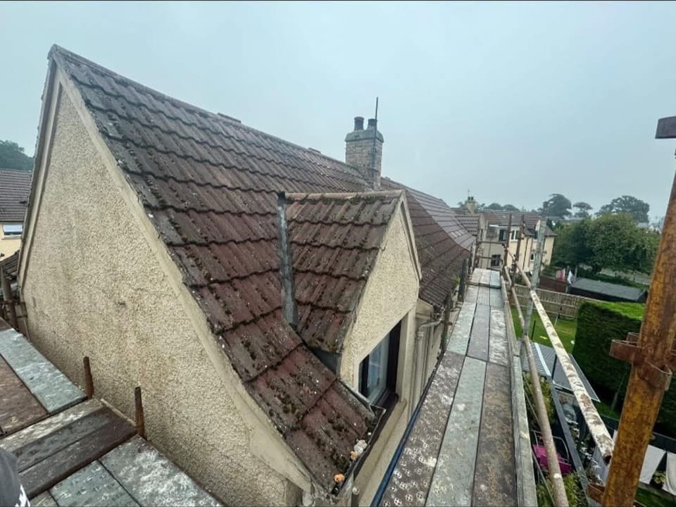 The gable and dormer before the re-roof, under old mossy pantiles.